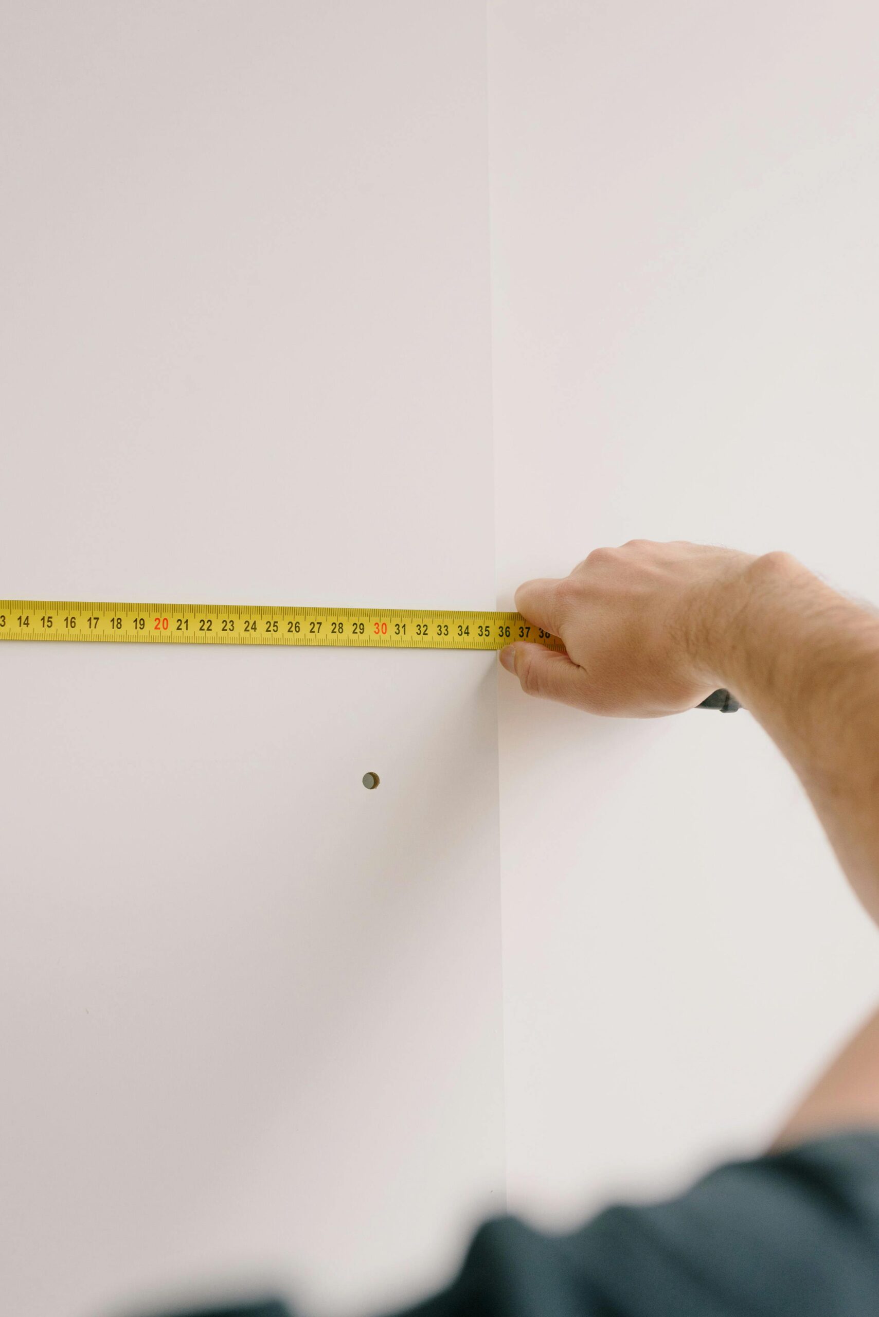 A hand measuring a wall for a home renovation, showcasing precision and skill.